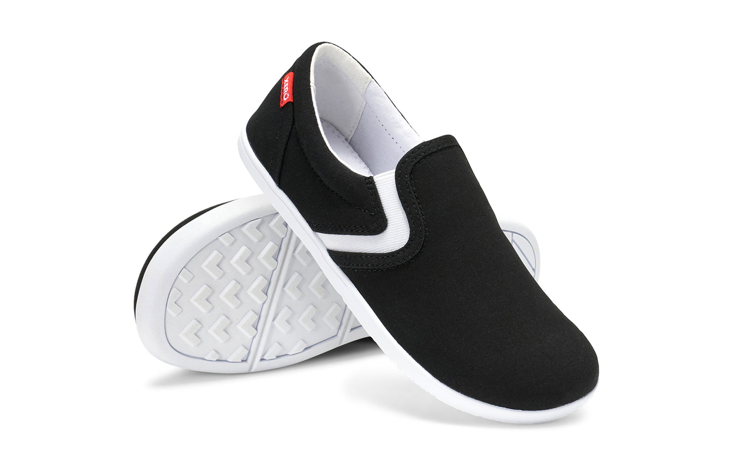 Xero Kid's Barefoot Shoes sold in Ontario, Canada. These minimalist shoes have flexible soles, wide toe boxes, and zero drop. Angled pair view of Xero Youth Dillon Canvas Slip-On in Black.
