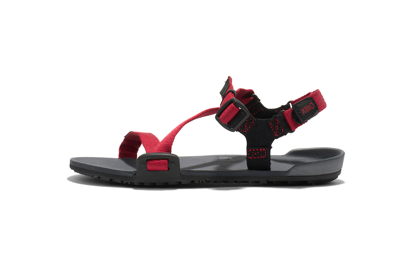 Xero Kid's Barefoot Shoes sold in Ontario, Canada. These minimalist shoes have flexible soles, wide toe boxes, and zero drop. Side view of Xero Kid's Z-Trail in Charcoal/Red Pepper, a lightweight packable sport sandal.