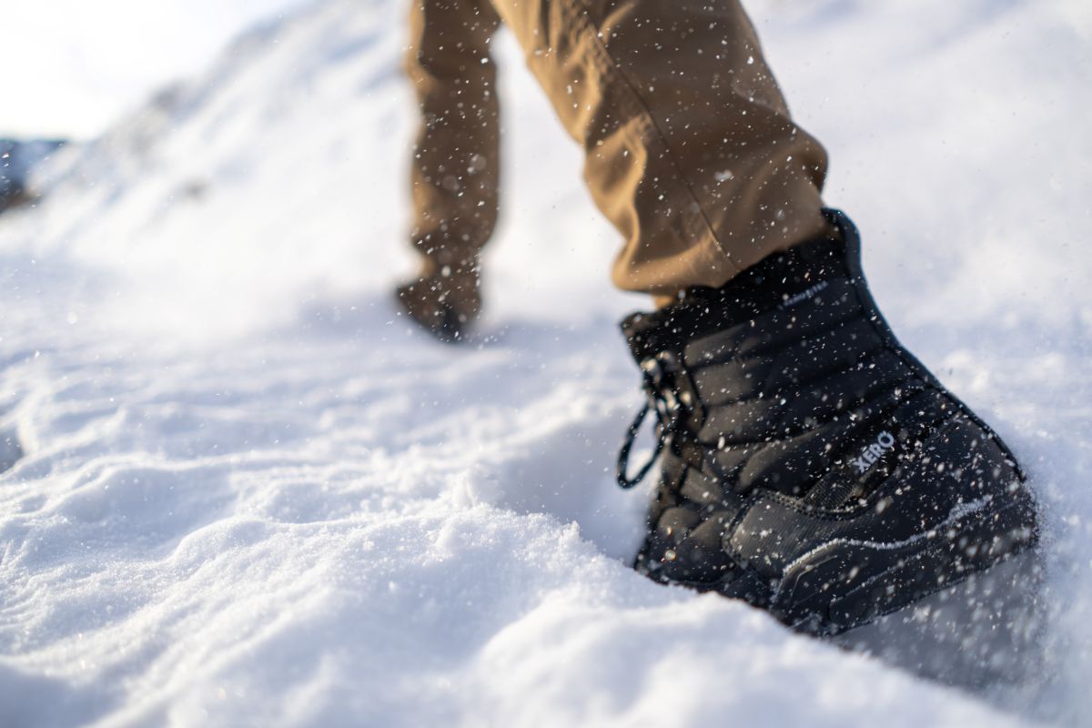 Black winter boot stepping into the snow. Tru Stride Co brings Xero Shoes to Canada