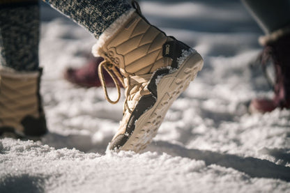 Beige winter boots with fur lining on a snowy ground. Tru Stride Co brings Xero Shoes to Canada