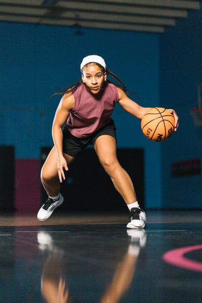 Woman holding a basketball on a court with a blue wall in the background. Tru Stride Co brings Xero Shoes to Canada