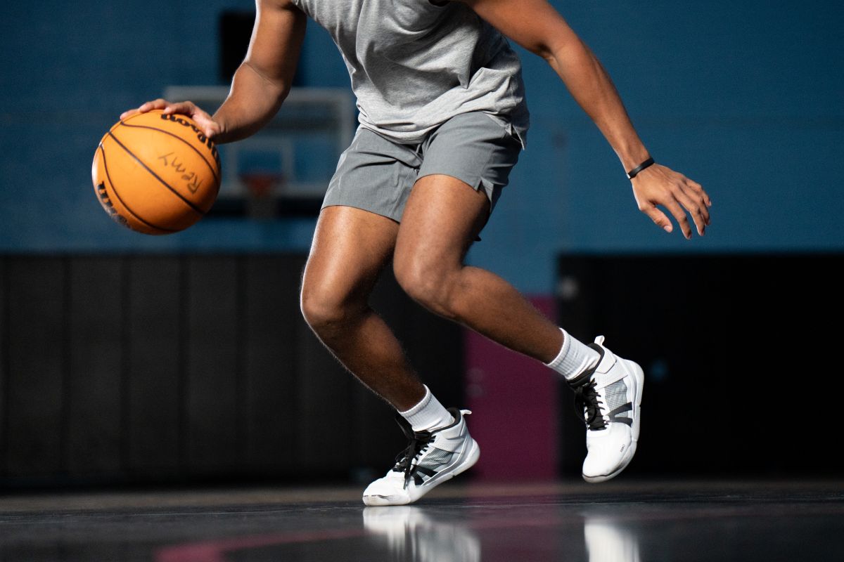 Person dribbling a basketball on a court with a dark background. Tru Stride Co brings Xero Shoes to Canada