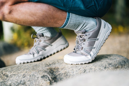 Xero Shoes Canada, specifically barefoot hiking shoes Canada. Man wearing Scambler Trail Low while crouching on a rock